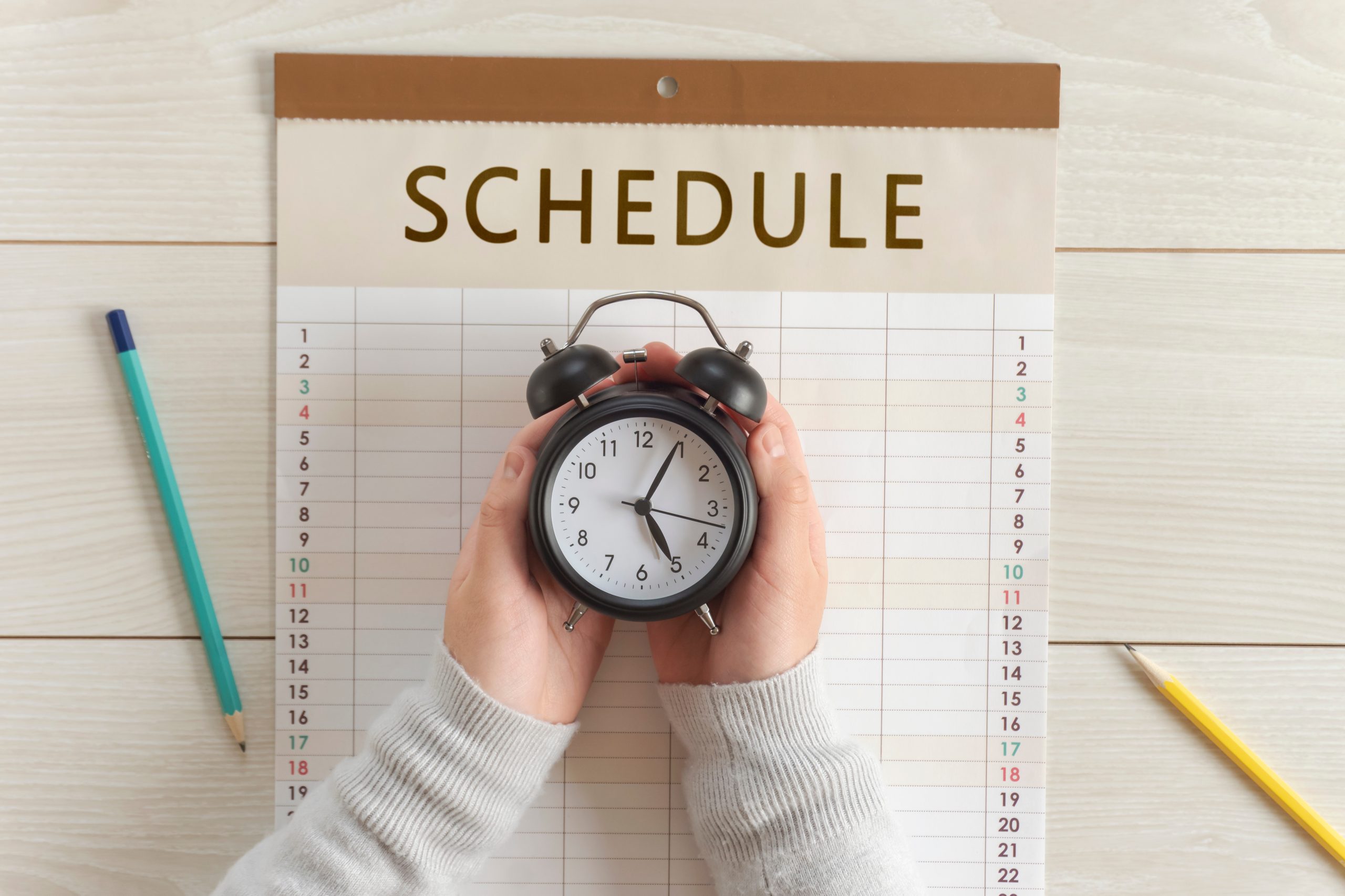 Girl’s hands holding clock on the calendar. Schedules, Plans, Reservations, Appointments, etc. カレンダーの上で時計を持つ女の子の手。予定、スケジュール、計画、予約など